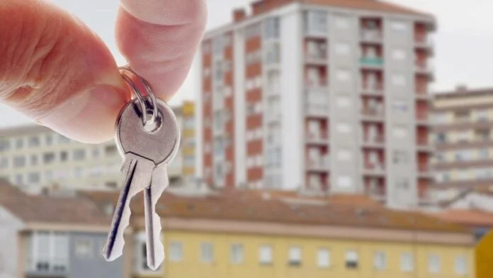 imagine cu o mana care tine o cheie, in fundal fiind blocuri ceea ce sugereaza piata imobiliara din Romania
